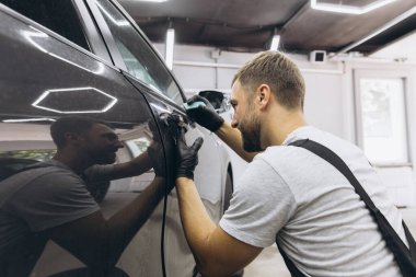 Yan vagon kapısındaki PPF kurulum işlemine yakın. PPF, boyayı çiziklerden ve taş parçalarından koruyan bir boya koruma filmidir. Gardiyan, Koruma, Araba, Yeni, İş.