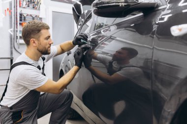 Yan vagon kapısındaki PPF kurulum işlemine yakın. PPF, boyayı çiziklerden ve taş parçalarından koruyan bir boya koruma filmidir. Gardiyan, Koruma, Araba, Yeni, İş.