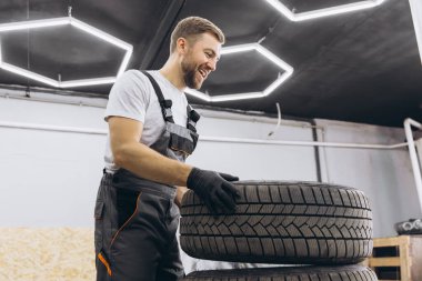 Tamirci değiştiren tekerlek, modern arabanın kış ve yaz lastikleri..