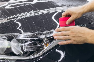 Araba ambalajlama uzmanı arabanın üzerine vinil folyo ya da film koyuyor..