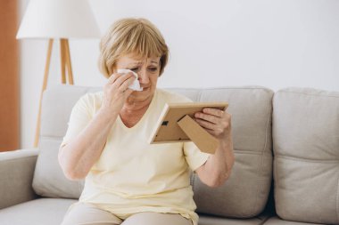 Depresyondaki yaşlı kadın elinde bir resim çerçevesi tutarak evde eski aile fotoğraflarını izliyor harap olmuş yaşlılar ağlıyor, kocasının ve oğlunun eski bir fotoğrafı için sızlanıyor, kayıp aşıklar, yalnızlık