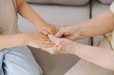 Büyükanne ve torunun el ele tutuşurken çekilmiş görüntüsü. Yaş ve nesil kavramı. Aile ilişkisi, sevgi, birleşme, birlik.