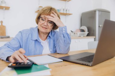 Şaşırmış son sınıf öğrencisi kadın kağıt döküman okuyor, anlaşma şartlarını gözden geçiriyor, faturaları ev masasında kontrol ediyor, hatalara kızıyor, fiyatlar çok yüksek, sorun var.