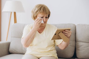 Depresyondaki yaşlı kadın elinde bir resim çerçevesi tutarak evde eski aile fotoğraflarını izliyor harap olmuş yaşlılar ağlıyor, kocasının ve oğlunun eski bir fotoğrafı için sızlanıyor, kayıp aşıklar, yalnızlık