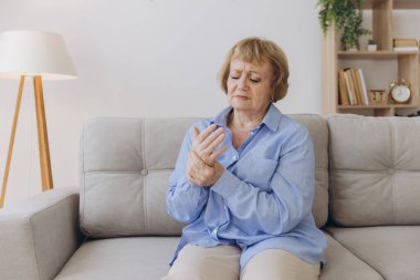 Elindeki ağrıdan muzdarip yaşlı kadın, eklem iltihabı, yaşlı kadın ve evde acı çeken yaşlı kadın.