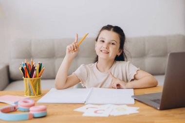 Küçük tatlı liseli kız boş alanda bir şey gösterip evde ödev yapıyor.