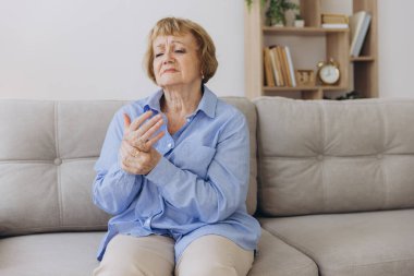 Elindeki ağrıdan muzdarip yaşlı kadın, eklem iltihabı, yaşlı kadın ve evde acı çeken yaşlı kadın.