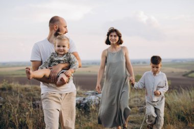 Neşeli bir aile birlikte dışarıda kaliteli zaman geçirir, güzel doğal bir manzarada mutluluk ve beraberlik anları yakalar..
