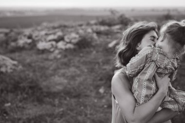 Anne ve çocuk arasında dokunaklı bir an siyah ve beyaz bir fotoğrafta çekildi, sevgiyi, sıcaklığı ve aile bağlarını sembolize eden açık hava ortamında.