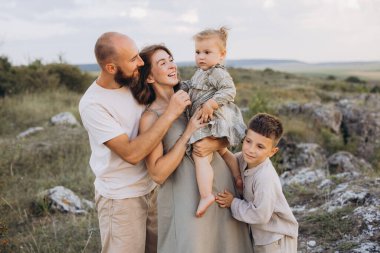 Neşeli bir aile, güneşli bir günde aşk ve mutluluk anları yakalayarak doğal bir ortamda birlikte vakit geçirir..