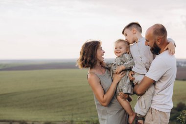Neşeli dört kişilik aile, güneşli bir günde güzel bir kırsal alana kurulmuş ve dışarıda kaliteli vakit geçiriyorlar..