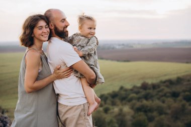 Üç kişilik neşeli bir aile gün batımında doğa manzarasının tadını çıkarıyorlar. Huzurlu bir manzara ortamında aşkı, sıcaklığı ve birlikteliği yakalamak..