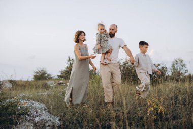 Neşeli bir aile güneşli bir günde çimenli bir tarlada dolaşır, beraberlik ve aşk anlarını doğal bir ortamda yakalar.
