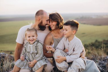 Neşeli aile gün batımında güzel bir kırsalda birlikte güzel zaman geçiriyorlar. Harika bir birliktelik ve mutluluk anı..