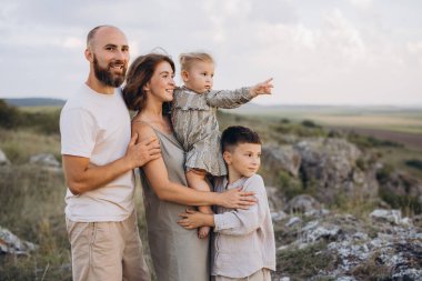 Neşeli bir aile, güzel, doğal bir ortamda bir arada durur. Kaliteli zaman geçirmenin ve açık gökyüzünün altında kaynaşmanın tadını çıkarırlar..