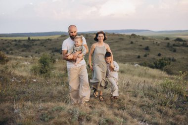 Dört kişilik neşeli bir aile, güneşli bir günde, temiz havanın ve güzel manzaranın tadını çıkarıyorlar..