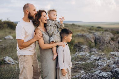 Dört kişilik neşeli bir aile doğada birlikte vakit geçiriyorlar. Anne babalar ve çocuklar huzurlu ve rahat görünürken açık hava ortamının tadını çıkarıyorlar..