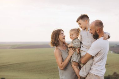 Manzaralı kırsal bölgede neşeli aile bağları kurarak ebeveynler ve çocuklar arasında sevgi dolu bir anı yakalıyorlar. Huzurlu manzara mutluluk ve birliktelik duygusunu arttırır..