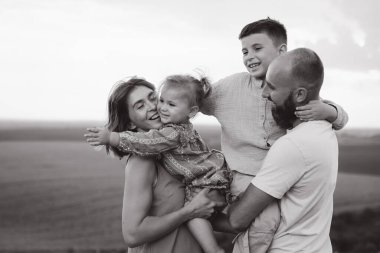 Neşeli bir ailenin siyah ve beyaz görüntüsü açık havada kaliteli zaman geçiriyor, mutluluk ve bağlantı anlarını yakalıyor..