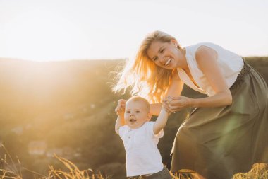 Neşeli bir anne ve çocuk dışarıda mutlu bir an paylaşıyorlar. Birlikte doğanın tadını çıkarırlarken güneş ışıl ışıl parlıyor. Barışçıl bir ortamda gülümsüyor ve kaynaşıyor..