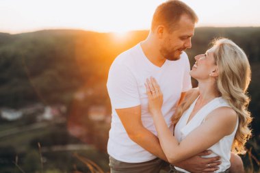 Sevgi dolu bir çift romantik ve birlikteliği simgeleyen çarpıcı bir tepede gün batımında kucaklaşır. Huzurlu manzara tutkulu ve samimi anı güçlendirir..