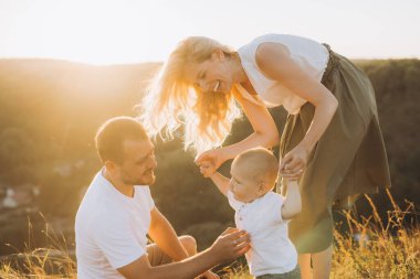 Neşeli bir aile sahnesi. Güneşli bir günde bir anne, baba ve çocuğun birbirine bağlandığı ve birlikte oynadığı..