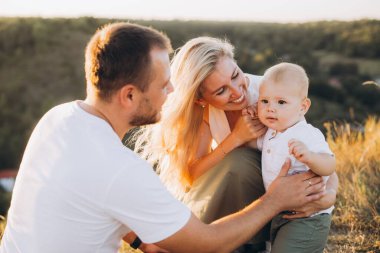 Neşeli bir aile, güneşli bir günde açık havada dinlenirken yürümekte olan çocuklarıyla bir anlık mutluluğu paylaşır..