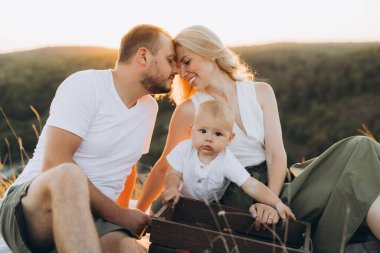 Mutlu bir aile gün batımında birlikte dışarıda oturur, anne ve babalarının küçük çocuklarını sevgiyle kucaklamalarını izlerler. Doğadaki aile sevgisinin, sıcaklığın ve birlikteliğin mükemmel bir tasviri..