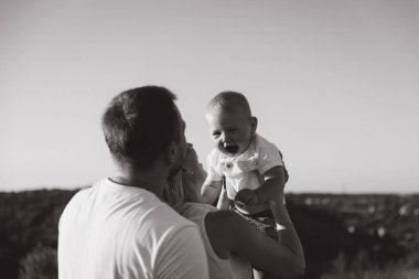 Sevgi dolu ebeveynler tarafından kucaklanırken mutlu bir bebeğin kahkahalarla güldüğü keyifli bir aile sahnesi güzel bir neşe ve bağlantı anı sergiliyor..