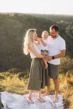 Neşeli bir aile, yemyeşil yemyeşil bir tepede güneşli bir günün tadını çıkararak birlikte kaliteli zaman geçirir..