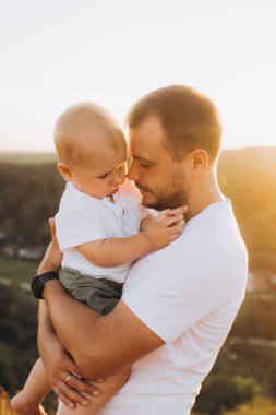 Sevgi dolu bir baba bebeğini kucağına alır ve gün batımında sıcak bir anı paylaşır. Ailenin şefkatini ve bağlantısını yakalar..