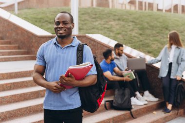 Üniversite öğrencileri kampüs basamaklarında çalışır ve işbirliği yaparlar. Bir öğrenci notları incelerken, diğerleri dizüstü bilgisayarlar ve defterlerle grup tartışması yapıyor..