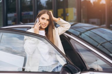 Kendine güvenen bir iş kadını arabasının yanında durmuş, telefonla konuşuyor. Şık bir kıyafet giyiyor. Kültürlü ve profesyonelliğin vücut bulmuş hali..