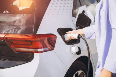 Modern sürdürülebilir ulaşımı ön plana çıkaran elektrikli bir aracı şarj eden birinin yakın çekimi. Görüntü, günlük kullanımda temiz enerji ve çevre dostu teknolojiyi vurguluyor.