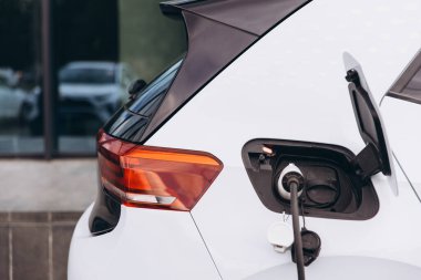Bir istasyonda şarj edilen elektrikli bir aracın detaylı görüntüsü, modern ulaşım ve sürdürülebilir enerji teknolojisi sergiliyor..