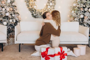 Noel 'de güzel bir şekilde paketlenmiş bir hediyeyi paylaşırken rahat süveter giymiş iki arkadaşın kucaklaşması çok iç açıcı bir sahne. Şenlik ortamı süslenmiş Noel ağaçlarıyla süslenmiş..