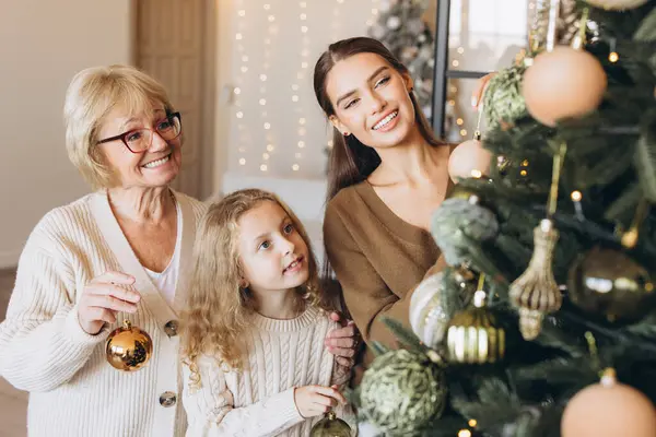 Noel ağacını süs eşyalarıyla süsleyerek, Noel sezonunda birliktelikle süsleyerek birbirine bağlanan üç neslin yer aldığı neşeli bir aile sahnesi. Aile kutlamasının mükemmel tasviri.