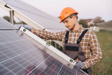 Yetenekli bir mühendis, bir seviye aracı kullanarak güneş paneli denetimi gerçekleştirir. Sahne, bir güneş çiftliğindeki yenilenebilir enerji bakımının hassasiyetini ve bakımını yakalıyor..