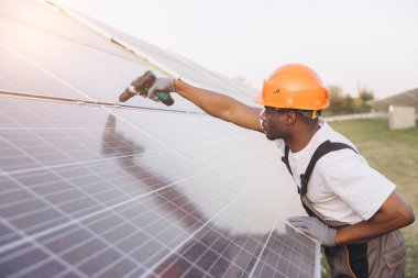 Profesyonel bir mühendis güneş panellerini açık alanda ayarlar. Görüntü yenilenebilir enerji, güneş enerjisi teknolojisi ve parlak güneş ışığı altında sürdürülebilir mühendislik çözümleri sergiliyor.