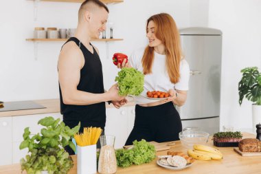 Mutlu gülümseyen birkaç sporcu evdeki mutfakta sağlıklı yemek hazırlıyor.