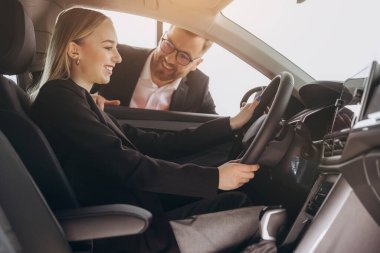 Mutlu yetişkin kadın alıcı - iş kadını - araba galerisinden yeni, modern bir araba almaktan zevk alıyor. Pahalı satın alma, kiralama ve test sürüşü kavramı.