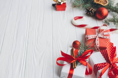 Noel kompozisyonu. Hediyeler, çam kozalakları, köknar dalları, şeker, baharatlar ve ahşap beyaz arka plandaki diğer süslemeler. Düz yatış, üst görünüm.