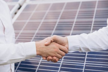 Güneş enerjisi istasyonundaki güneş panellerinin kurulumu ve bakımını denetlemek için çalıştıktan sonra iki Elektrik Mühendisi el sıkışıyor.