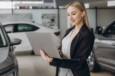Araba galerisinde dizüstü bilgisayar kullanan başarılı satış elemanı portresi
