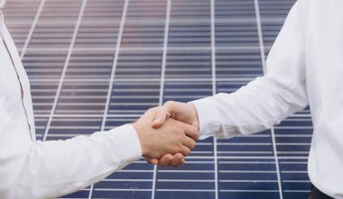 Güneş enerjisi istasyonundaki güneş panellerinin kurulumu ve bakımını denetlemek için çalıştıktan sonra iki Elektrik Mühendisi el sıkışıyor.