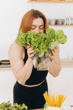 Diş teli takan olgun kaslı kadın evde salata yaprakları tutuyor.