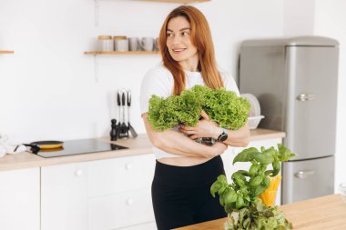 Diş teli takan olgun kaslı kadın evde salata yaprakları tutuyor.