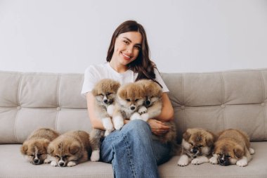 Mutlu gülümseyen milenyum kadınlarının portresi. Evdeki kanepede Akita Inu yavrularını kucaklayıp oynuyorlar.