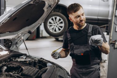 Tamirci, servis merkezindeki motor yağı seviyesini kontrol ediyor.