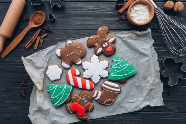 Ren geyiği, zencefilli ekmek ve Noel ağacı şekilleri de dahil olmak üzere çeşitli süslü Noel kurabiyeleri ahşap kaplar ve baharatlarla sade pişme kağıtlarında düzenlenmiştir..